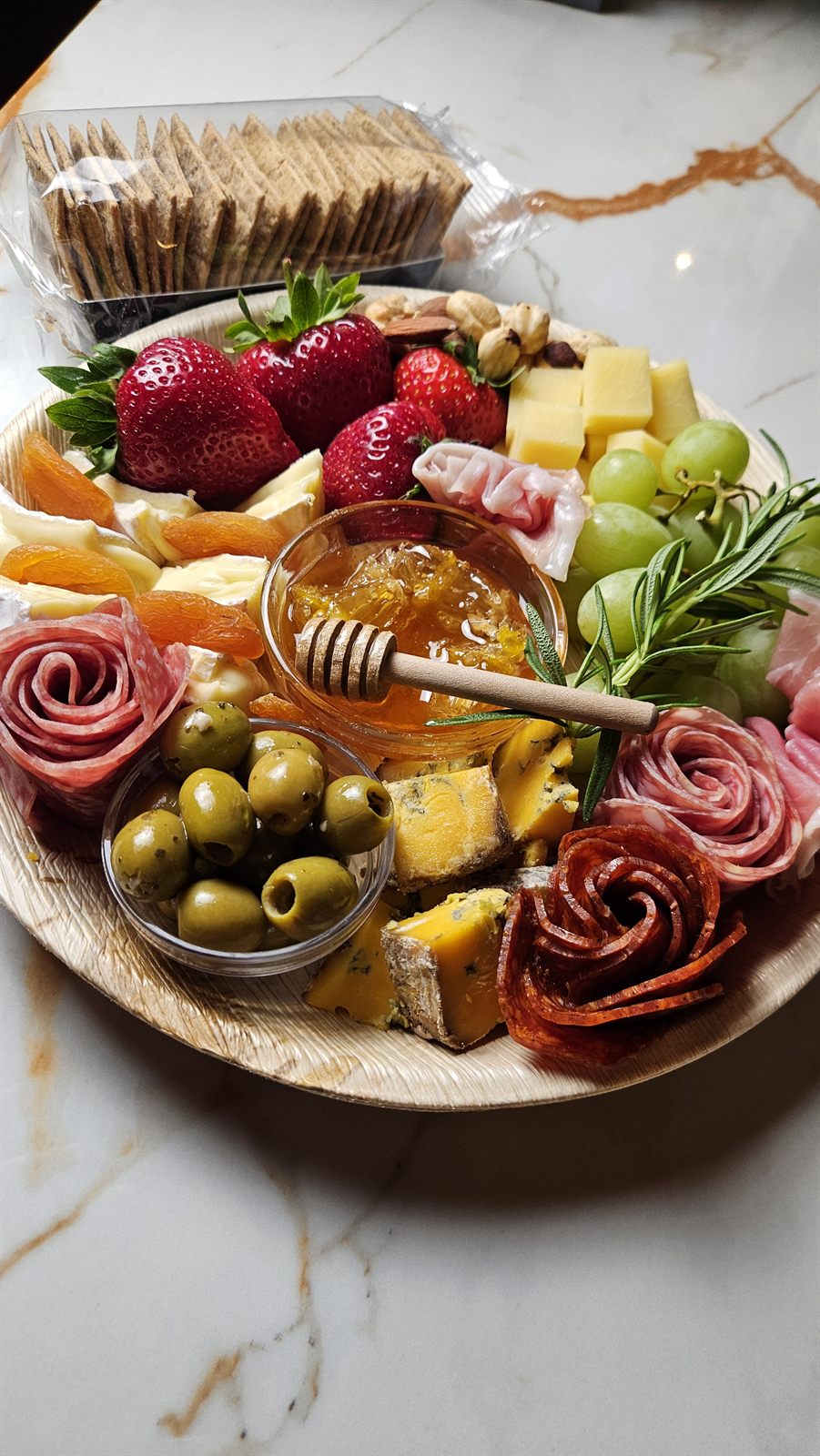 A full Social Nibble grazing board with charcuterie roses, cheeses, honey, olives and fruit