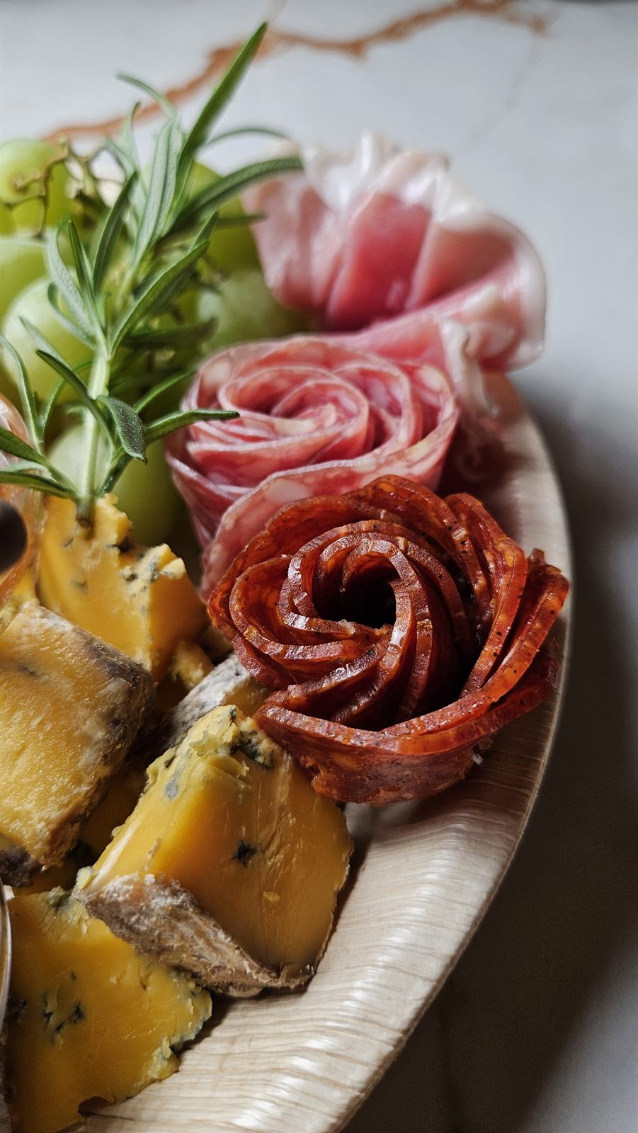 Close-up of a Social Nibble board with chorizo and salami roses, blue cheese and rosemary